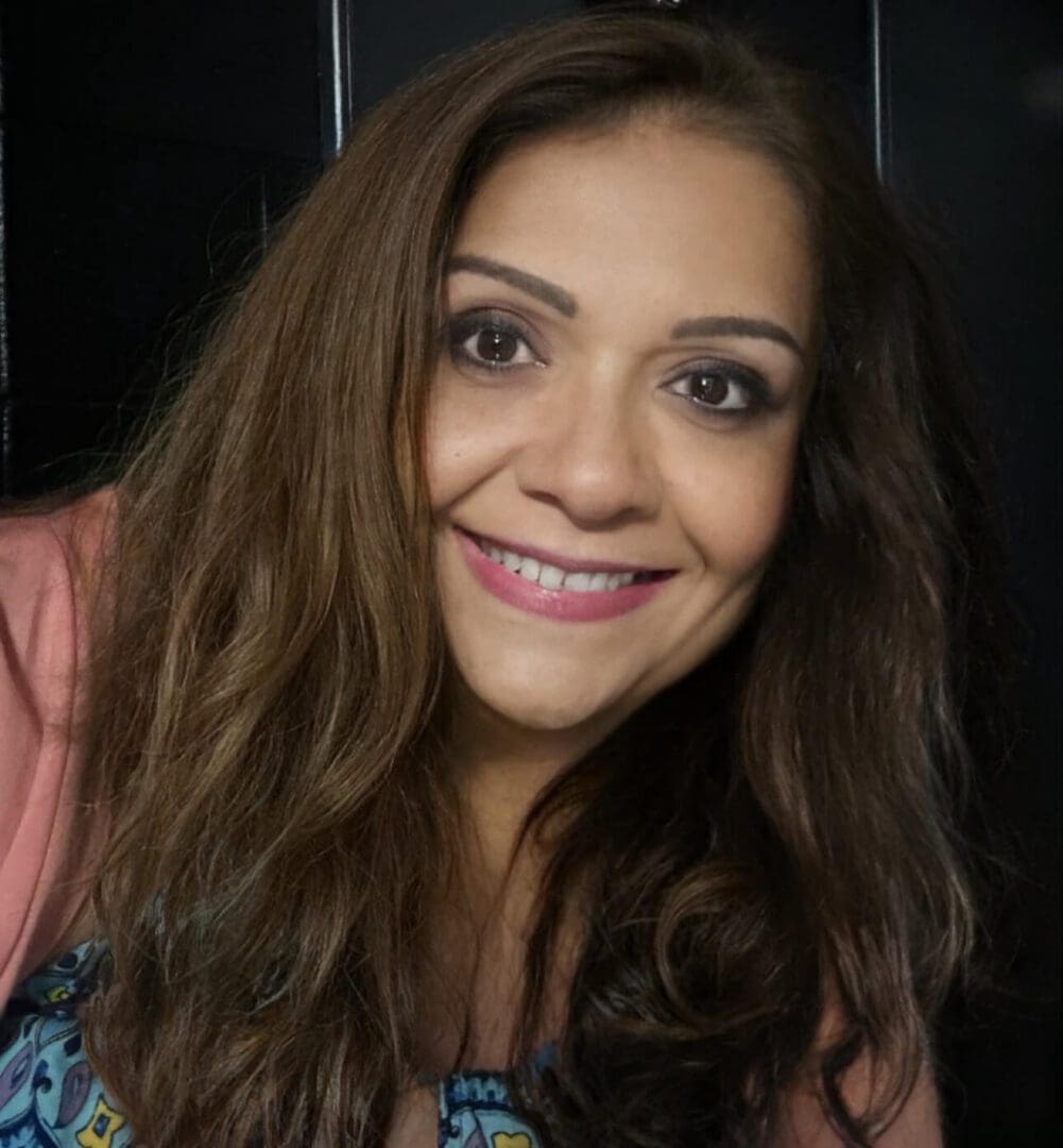 A woman with long brown hair smiles for the camera.