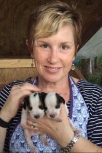 A woman holding two puppies in her arms.