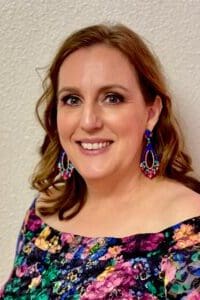 A woman with long hair and blue earrings.