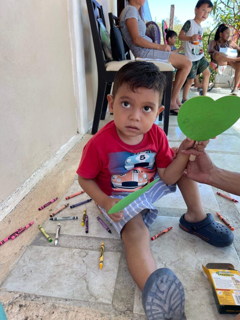 A little boy sitting on the floor holding a green object.