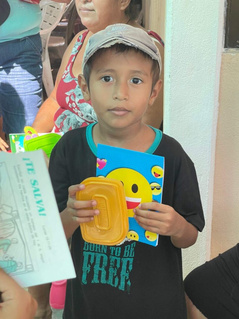 A young boy holding an open book and a yellow smile face.