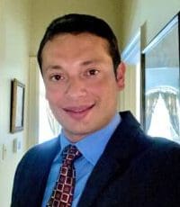 A man in a suit and tie smiling for the camera.