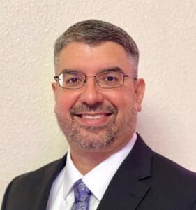 A man in a suit and tie smiling for the camera.