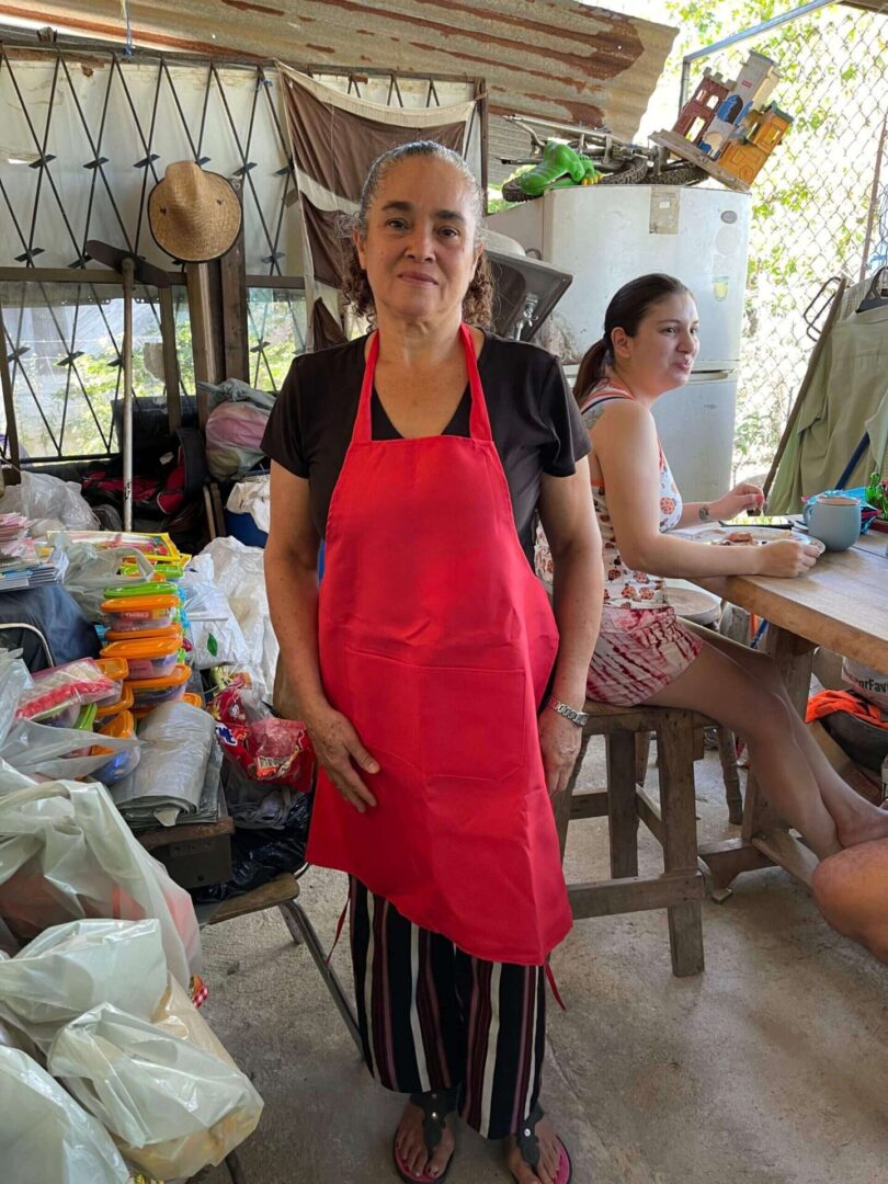 A woman in an apron standing next to some people.